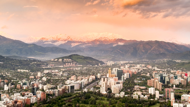 Aerial view of the Santiago skyline with modern skyscrapers green parks and snow capped Andes mountains under a warm sunset sky in Santiago Santiago Metropolitan Chile. Aerial view of the Santiago skyline with modern skyscrapers green parks and snow capped Andes mountains under a warm sunset sky in Santiago Santiago Metropolitan Chile.
