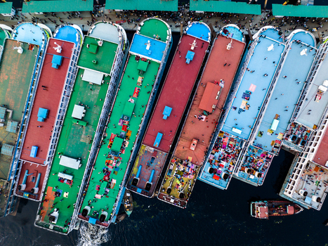 Aerial view of Sadarghat ferry terminal with colorful passenger boats docked along the Buriganga River featuring busy decks with people in Dhaka Dhaka Division Bangladesh. Aerial view of Sadarghat ferry terminal with colorful passenger boats docked along the Buriganga River featuring busy decks with people in Dhaka Dhaka Division Bangladesh.