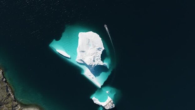 Aerial view of iceberg and boat in the waters of Greenland. Aerial view of iceberg and boat in the waters of Greenland.
