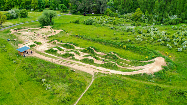 Aerial view of Monkey Island Dirt Park featuring dirt bike tracks and jumps surrounded by lush green meadows and trees in Forchheim Bayern Germany.