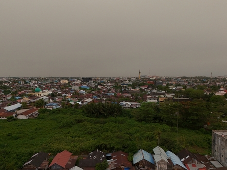 Aerial view of the urban landscape of Banjarmasin City with dense rooftops lush greenery and a hazy sky in Banjarmasin City South Kalimantan Indonesia. Aerial view of the urban landscape of Banjarmasin City with dense rooftops lush greenery and a hazy sky in Banjarmasin City South Kalimantan Indonesia.