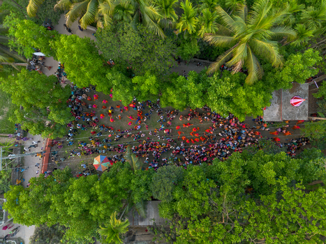 Munshiganj Bangladesh 13 April 2026 Aerial view of a vibrant sea of people many adorned in striking red gathered amidst the emerald canopy of dense tropical trees.