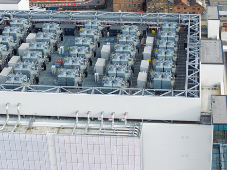 Aerial view of a data center roof featuring numerous industrial cooling units ventilation systems and complex piping infrastructure in the United Kingdom. Aerial view of a data center roof featuring numerous industrial cooling units ventilation systems and complex piping infrastructure in the United Kingdom.