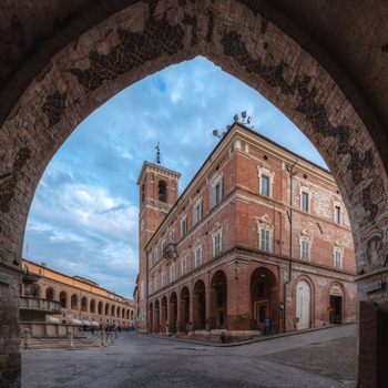 View of the historic Piazza del Comune with its iconic brick buildings arched porticos and cobblestone square under a blue sky in Fabriano Marche Italy. View of the historic Piazza del Comune with its iconic brick buildings arched porticos and cobblestone square under a blue sky in Fabriano Marche Italy.
