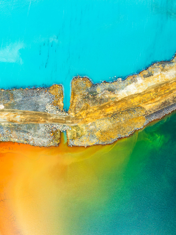 Aerial view of a vibrant turquoise tailings pond separated by a rocky causeway from a deep green and orange mineral rich water basin in Andalusia Spain. Aerial view of a vibrant turquoise tailings pond separated by a rocky causeway from a deep green and orange mineral rich water basin in Andalusia Spain.