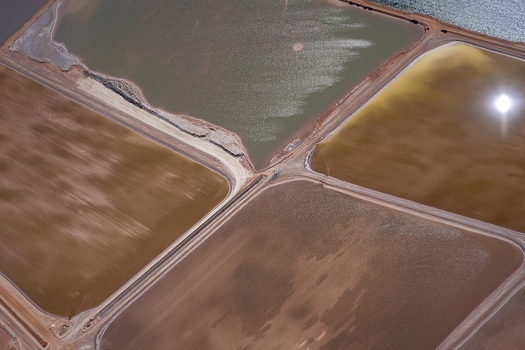 Aerial view of salt evaporation ponds with varying shades of brown tan and green water separated by dirt embankments in Australia. Aerial view of salt evaporation ponds with varying shades of brown tan and green water separated by dirt embankments in Australia.