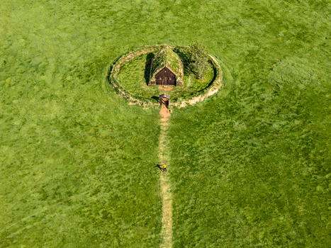 Aerial view of a traditional Icelandic turf church surrounded by a circular earthen wall in a vast green field with a person standing on a path Iceland. Aerial view of a traditional Icelandic turf church surrounded by a circular earthen wall in a vast green field with a person standing on a path Iceland.