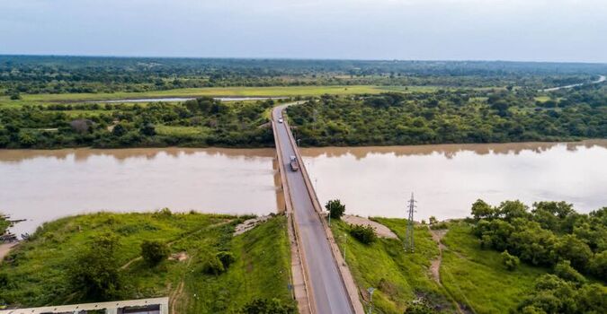 Aerial view of a bridge spanning a wide river turned to muddy color as a result of illegal mining surrounded by lush green vegetation and trees in the rural landscape of Northern Ghana close to Tamale Aerial view of a bridge spanning a wide river turned to muddy color as a result of illegal mining surrounded by lush green vegetation and trees in the rural landscape of Northern Ghana close to Tamale
