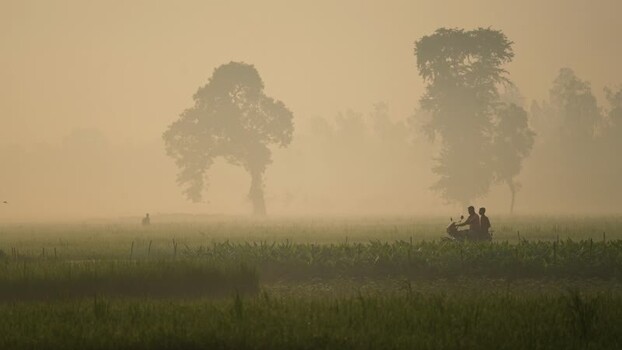 View of people on a motorcycle in a misty field Bangladesh. View of people on a motorcycle in a misty field Bangladesh.