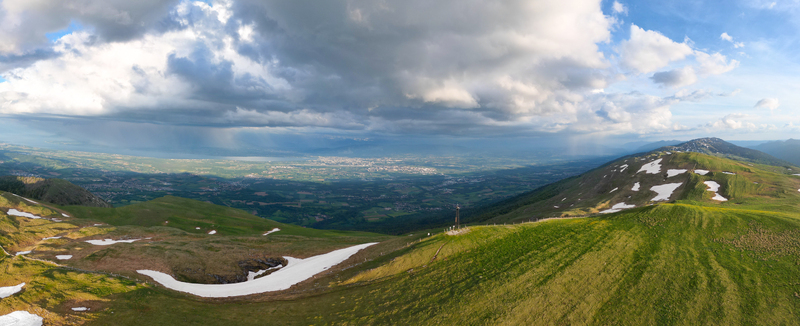Aerial view of Le Colomby de Gex mountain peak with green slopes and patches of snow overlooking the valley and Lake Geneva Echenevex Auvergne Rhone Alpes France. Aerial view of Le Colomby de Gex mountain peak with green slopes and patches of snow overlooking the valley and Lake Geneva Echenevex Auvergne Rhone Alpes France.
