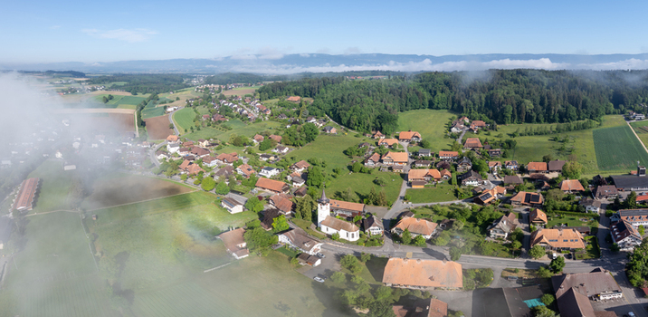 Aerial view of the village of Grossaffoltern with its historic church traditional houses and surrounding green fields under a light morning mist Grossaffoltern Canton of Bern Switzerland. Aerial view of the village of Grossaffoltern with its historic church traditional houses and surrounding green fields under a light morning mist Grossaffoltern Canton of Bern Switzerland.