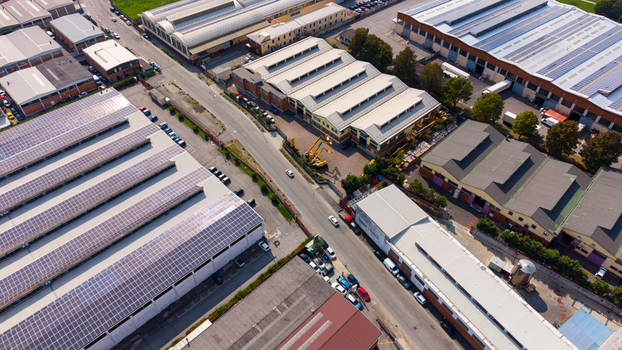 Aerial view of an industrial zone featuring large warehouses with solar panels on their roofs paved roads and parked cars in Milan Lombardy Italy.