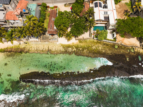 Aerial view of Thalpe Beach featuring natural rock pools turquoise ocean waves and coastal villas surrounded by lush palm trees in Talpe Southern Province Sri Lanka. Aerial view of Thalpe Beach featuring natural rock pools turquoise ocean waves and coastal villas surrounded by lush palm trees in Talpe Southern Province Sri Lanka.