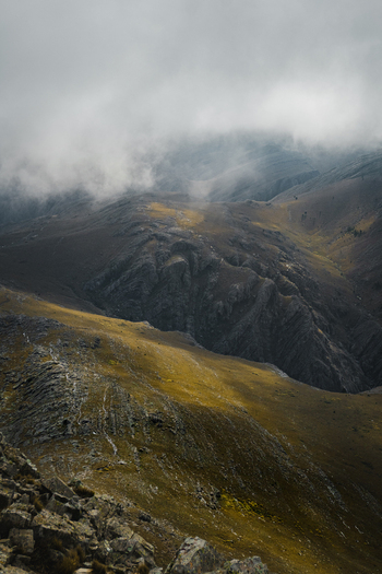 View of rugged mountain slopes with low hanging clouds rocky terrain and golden grass under a moody sky Sierra de La Ventana Buenos Aires Province Argentina. View of rugged mountain slopes with low hanging clouds rocky terrain and golden grass under a moody sky Sierra de La Ventana Buenos Aires Province Argentina.