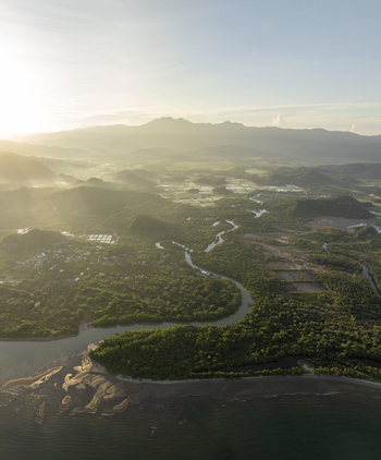 Aerial view of a winding river flowing through lush mangroves and coastal landscape near Labuan Bajo with distant mountains under soft morning light in Komodo East Nusa Tenggara Indonesia. Aerial view of a winding river flowing through lush mangroves and coastal landscape near Labuan Bajo with distant mountains under soft morning light in Komodo East Nusa Tenggara Indonesia.