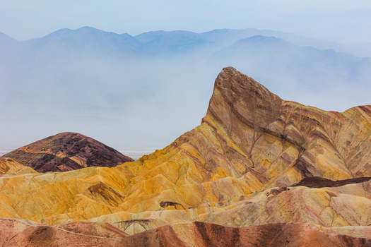 View of the colorful eroded badlands and sedimentary rock formations at Death Valley National Park in the United States.