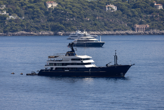 Aerial view of luxury yachts anchored in the blue waters off the coast of Monaco City with lush green hills and coastal villas in the background Monaco Monaco.