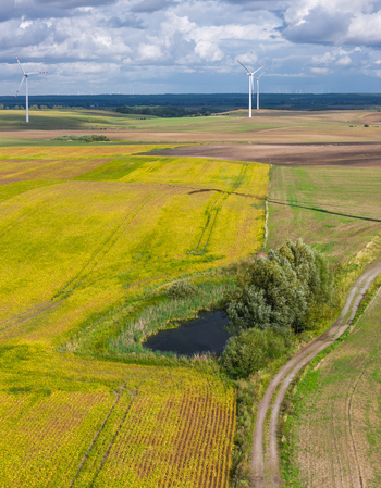 Aerial view of Kashubia landscape featuring wind turbines agricultural fields and a small pond in Pelplin Pomeranian Voivodeship Poland.