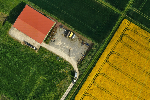 Aerial view of a farm building with a red roof surrounded by vibrant green and yellow agricultural fields Hofgeismar Hessen Germany. Aerial view of a farm building with a red roof surrounded by vibrant green and yellow agricultural fields Hofgeismar Hessen Germany.