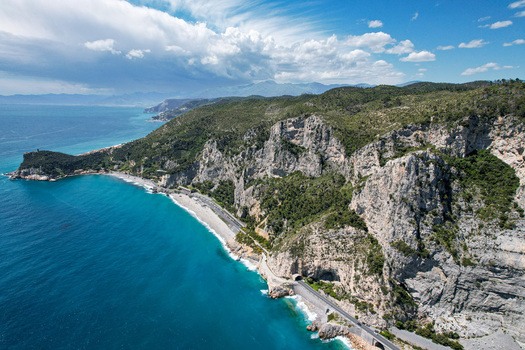 Aerial view of the Promontorio di Varigotti with steep limestone cliffs overlooking the turquoise sea and coastal road Varigotti Liguria Italy. Aerial view of the Promontorio di Varigotti with steep limestone cliffs overlooking the turquoise sea and coastal road Varigotti Liguria Italy.