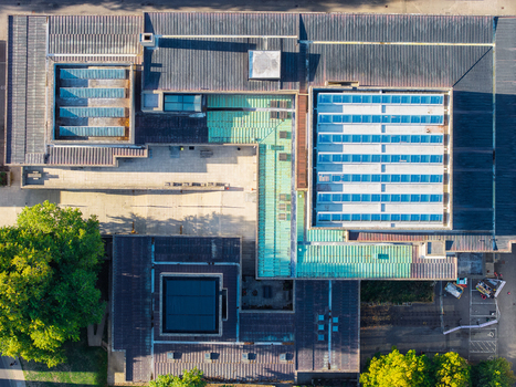 Aerial view of the Data Center at Oxford University featuring a complex roof structure with skylights and green metal panels surrounded by trees in Oxford England United Kingdom. Aerial view of the Data Center at Oxford University featuring a complex roof structure with skylights and green metal panels surrounded by trees in Oxford England United Kingdom.