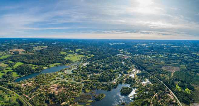 Aerial view of the lush green Latvian landscape featuring winding rivers dense forests and scattered lakes under a bright blue sky Latvia. Aerial view of the lush green Latvian landscape featuring winding rivers dense forests and scattered lakes under a bright blue sky Latvia.
