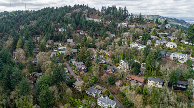 Aerial view of Northwest Imperial Terrace featuring residential houses on a lush green hillside with dense forest and winding roads in Portland Oregon United States. Aerial view of Northwest Imperial Terrace featuring residential houses on a lush green hillside with dense forest and winding roads in Portland Oregon United States.