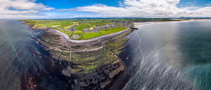 Aerial view of Storm Beach with its rugged rocky shoreline adjacent green fields and the coastal town of Carrownedin in County Sligo Ireland.