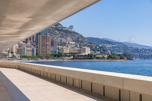 View of the Monaco coastline with modern high rise buildings the Mediterranean Sea and a clean concrete promenade in Monaco City Monaco. View of the Monaco coastline with modern high rise buildings the Mediterranean Sea and a clean concrete promenade in Monaco City Monaco.