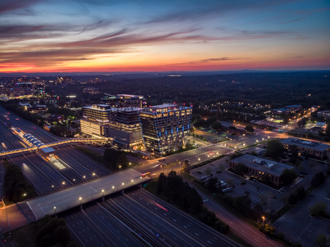 Reston Virginia United States 27 May 2020 Aerial view of modern office buildings illuminated at dusk with a vibrant sunset sky highway light trails and a pedestrian bridge. Reston Virginia United States 27 May 2020 Aerial view of modern office buildings illuminated at dusk with a vibrant sunset sky highway light trails and a pedestrian bridge.