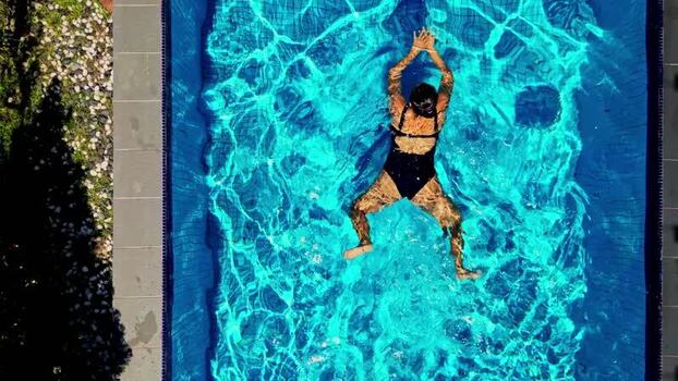 Aerial view of a woman swimming in a blue pool Malaysia.