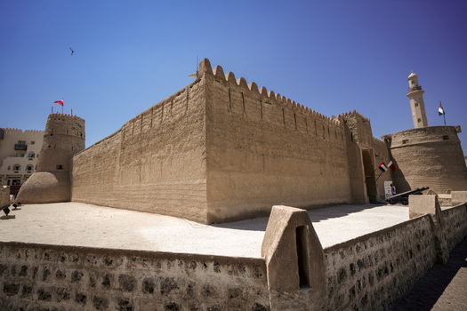 View of Al Fahidi Fort with its historic mud brick walls and defensive towers under a clear blue sky in Dubai Dubai United Arab Emirates. View of Al Fahidi Fort with its historic mud brick walls and defensive towers under a clear blue sky in Dubai Dubai United Arab Emirates.