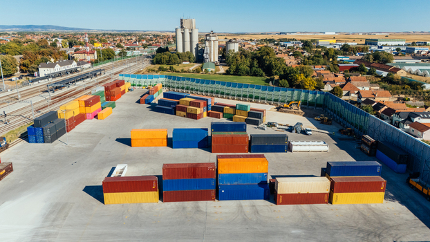 Indjija Serbia 24 August 2026 Aerial view of a shipping container yard with colorful containers stacked in rows adjacent to railway tracks and industrial silos under a clear blue sky.