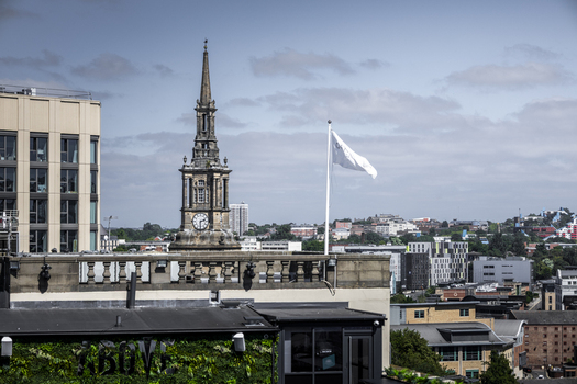 View of the historic St. Nicholas Cathedral clock tower rising above modern urban rooftops and a green wall in Newcastle upon Tyne England United Kingdom. View of the historic St. Nicholas Cathedral clock tower rising above modern urban rooftops and a green wall in Newcastle upon Tyne England United Kingdom.