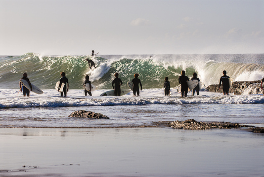 View of surfers standing in the water with surfboards facing a breaking wave at Snapper Rocks in Coolangatta Queensland Australia.