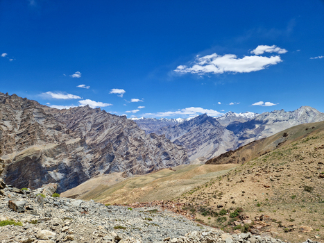 View of Penzi La road winding through the rugged arid mountain landscape of the Himalayas under a clear blue sky in Zanskar Ladakh India.