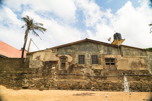 View of an old weathered building with stone walls and a palm tree under a cloudy sky in Galle Southern Province Sri Lanka.