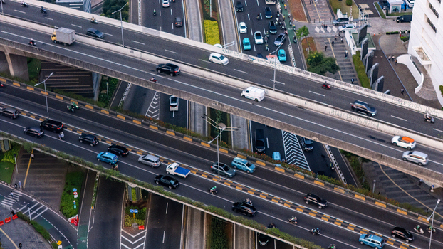 Aerial view of the busy multi level highway interchange featuring heavy traffic flow with cars and motorcycles navigating the concrete overpasses in Jakarta Indonesia.