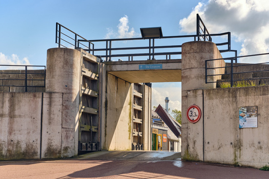Den Oever Netherlands 18 May 2026 View of the De Coupure floodgate in the sea dike at Vissershaven with concrete walls and black metal railings under a blue sky. Den Oever Netherlands 18 May 2026 View of the De Coupure floodgate in the sea dike at Vissershaven with concrete walls and black metal railings under a blue sky.