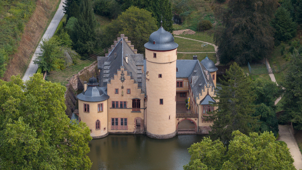 Aerial view of Schloss Mespelbrunn a historic water castle surrounded by lush trees and a moat in Mespelbrunn Bayern Germany.