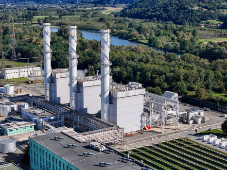 Aerial view of the A2A Chivasso Power Plant featuring three tall white chimneys and industrial structures near the river and green hills in Chivasso Piemonte Italy. Aerial view of the A2A Chivasso Power Plant featuring three tall white chimneys and industrial structures near the river and green hills in Chivasso Piemonte Italy.