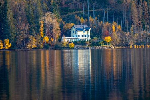 View of a yellow house on the shore of a calm lake surrounded by colorful autumn trees and forest in Breitnau Baden Wurttemberg Germany. View of a yellow house on the shore of a calm lake surrounded by colorful autumn trees and forest in Breitnau Baden Wurttemberg Germany.