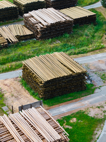 Aerial view of stacked timber logs in a lumber yard surrounded by green grass and paved paths in Brankas Jelgava Municipality Latvia. Aerial view of stacked timber logs in a lumber yard surrounded by green grass and paved paths in Brankas Jelgava Municipality Latvia.