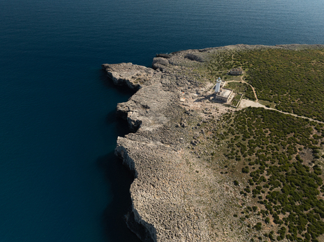 Aerial view of the Capo Murro di Porco lighthouse standing on the rugged rocky cliffs of the Plemmirio Marine Protected Area Plemmirio Sicily Italy. Aerial view of the Capo Murro di Porco lighthouse standing on the rugged rocky cliffs of the Plemmirio Marine Protected Area Plemmirio Sicily Italy.