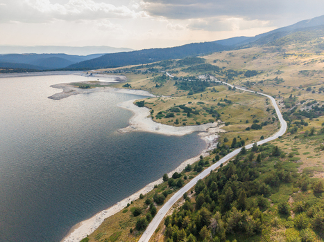 Aerial view of Belmeken reservoir with a winding road along the shoreline pine forests and rolling hills Pazardzhik Bulgaria. Aerial view of Belmeken reservoir with a winding road along the shoreline pine forests and rolling hills Pazardzhik Bulgaria.