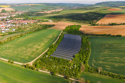 Aerial view of a solar panel farm surrounded by lush green trees and rolling agricultural fields Kyjov South Moravian Region Czechia.