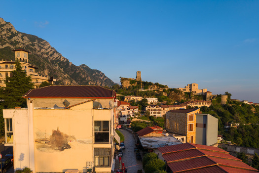 Kruje Albania 12 June 2026 Aerial view of Kruje Castle on a rocky hill overlooking the historic town and the rugged Kruje mountains under a clear blue sky at sunset.