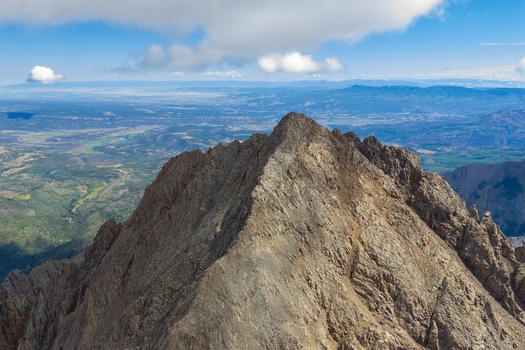 Aerial view of the rugged peak of Mount Sneffels in the San Juan Mountains with rocky slopes and an expansive valley landscape in Ouray County Colorado United States. Aerial view of the rugged peak of Mount Sneffels in the San Juan Mountains with rocky slopes and an expansive valley landscape in Ouray County Colorado United States.