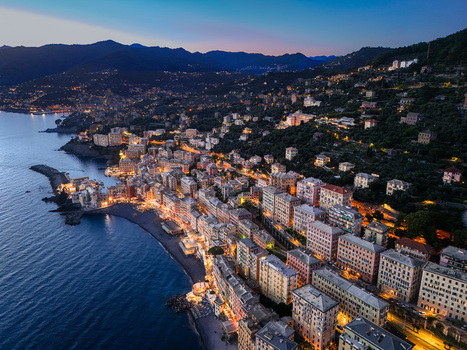 Aerial view of the illuminated waterfront and historic basilica with colorful buildings and dark hills at dusk in Camogli Liguria Italy. Aerial view of the illuminated waterfront and historic basilica with colorful buildings and dark hills at dusk in Camogli Liguria Italy.