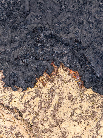 Aerial view of solidified black lava flow contrasting with light volcanic terrain in Iceland. Aerial view of solidified black lava flow contrasting with light volcanic terrain in Iceland.